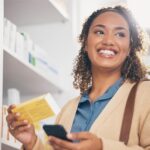 Mulher segura sorridente um medicamento ao usar o benefício farmácia, um de seus benefícios corporativos