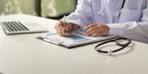 Médico do Santa Casa escrevendo em prancheta, plano apoiado pela Prospera Funcional